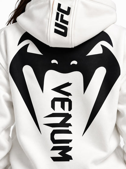Detalle de estampado grande Venum negro y logo UFC en capota de hoodie blanco